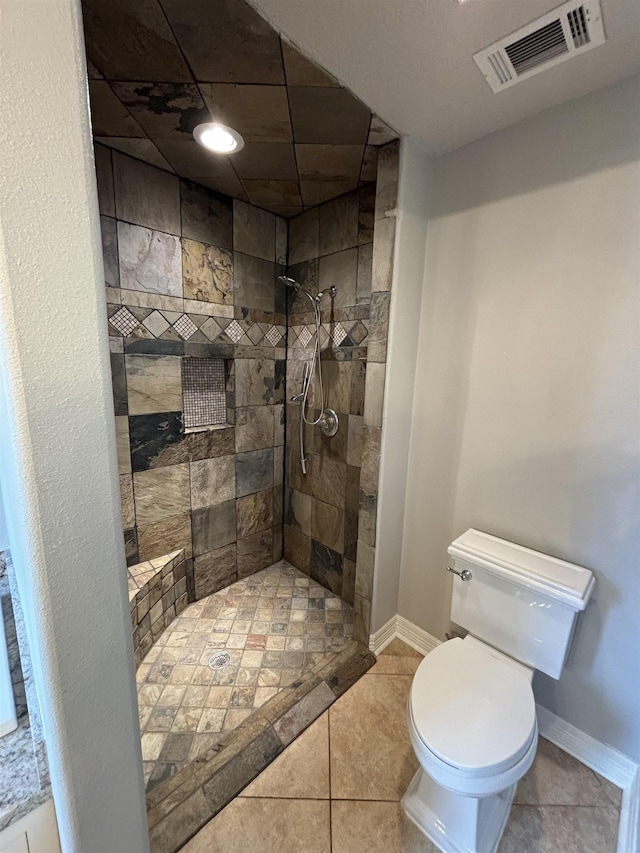 bathroom featuring tile patterned floors, a tile shower, and toilet