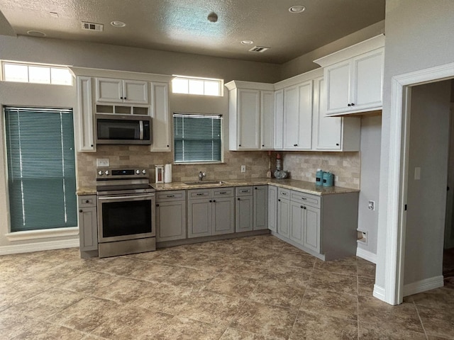 kitchen with backsplash, sink, a healthy amount of sunlight, and appliances with stainless steel finishes