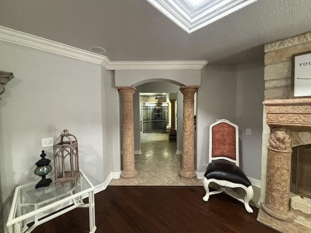 hallway with decorative columns, crown molding, hardwood / wood-style floors, and a textured ceiling