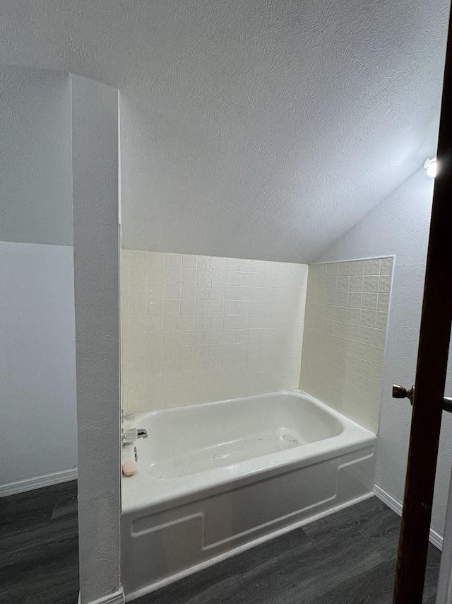 bathroom with hardwood / wood-style floors, a bathtub, and lofted ceiling