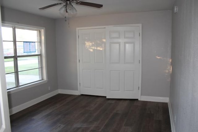 unfurnished bedroom with multiple windows, a closet, dark hardwood / wood-style floors, and ceiling fan