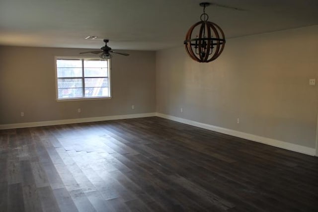 spare room featuring ceiling fan with notable chandelier and dark hardwood / wood-style floors