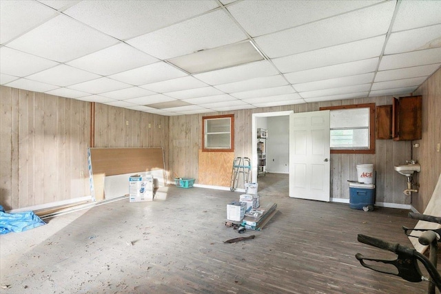 basement with dark hardwood / wood-style floors, a drop ceiling, and wood walls