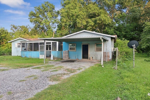 bungalow featuring a front lawn, a carport, and a sunroom