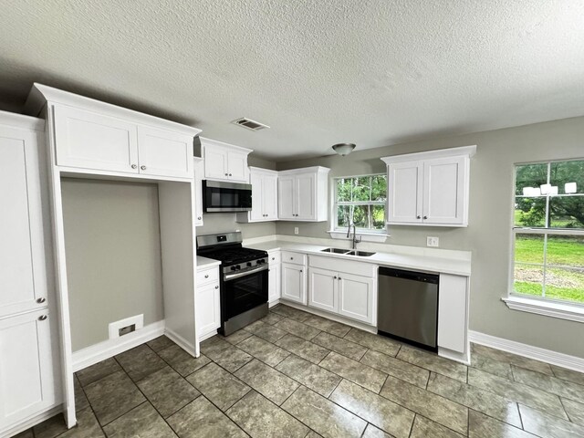 512 N Inwood Dr, Bridge City, TX 77611 - kitchen with white cabinets, appliances with stainless steel finishes, a sink, light countertops, and visible vents