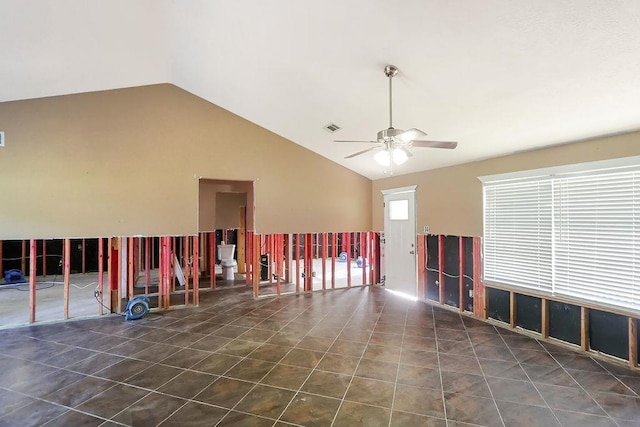 unfurnished room featuring ceiling fan, dark tile patterned floors, and lofted ceiling