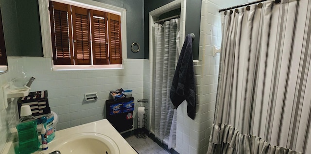 bathroom with a shower with curtain, tile walls, wainscoting, and a sink