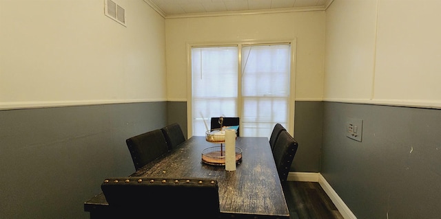 dining space featuring baseboards, visible vents, ornamental molding, and wood finished floors