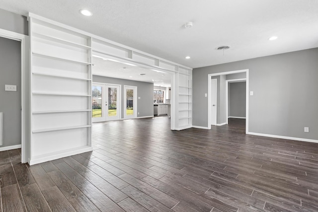 unfurnished living room with built in features, dark hardwood / wood-style flooring, and french doors