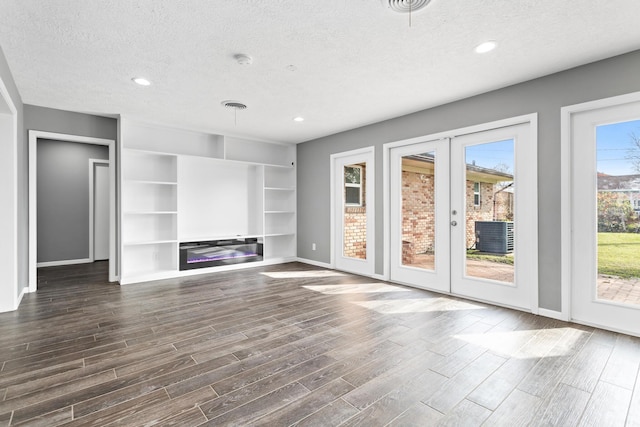 unfurnished living room featuring dark hardwood / wood-style flooring, french doors, and a textured ceiling