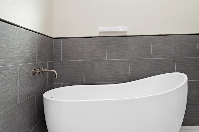 bathroom featuring a washtub and tile walls