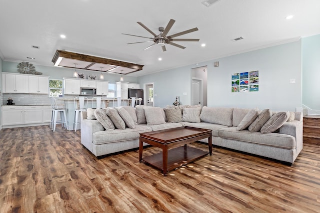 living room featuring ceiling fan, crown molding, and dark wood-type flooring