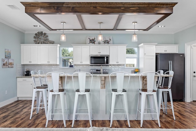 kitchen featuring white cabinetry, light stone counters, decorative light fixtures, a kitchen island, and appliances with stainless steel finishes