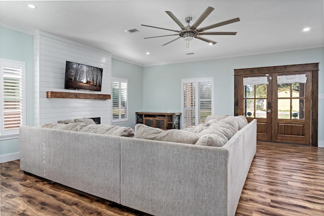 living room featuring a large fireplace, dark hardwood / wood-style flooring, french doors, and ornamental molding