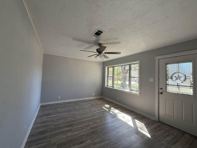 entrance foyer featuring a textured ceiling, ornamental molding, dark wood finished floors, and visible vents