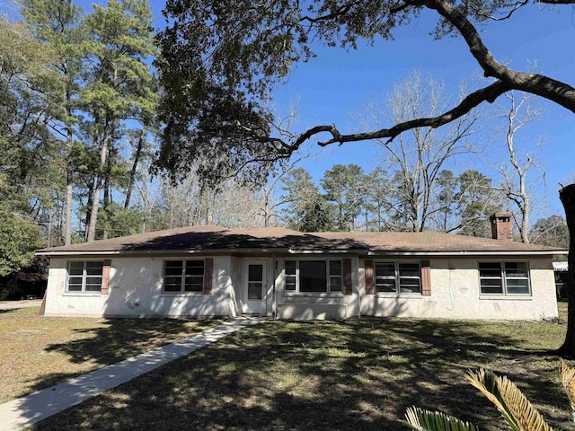single story home with a front lawn, a chimney, and stucco siding