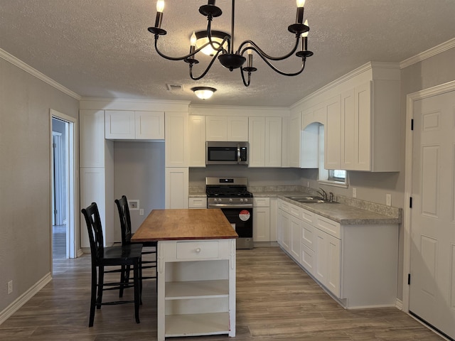kitchen with stainless steel appliances, wood counters, visible vents, open shelves, and an inviting chandelier