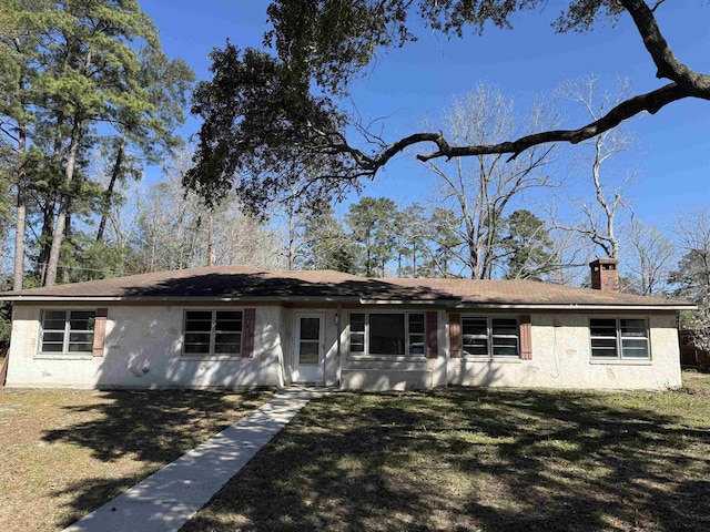 ranch-style house featuring a chimney, a front lawn, and stucco siding