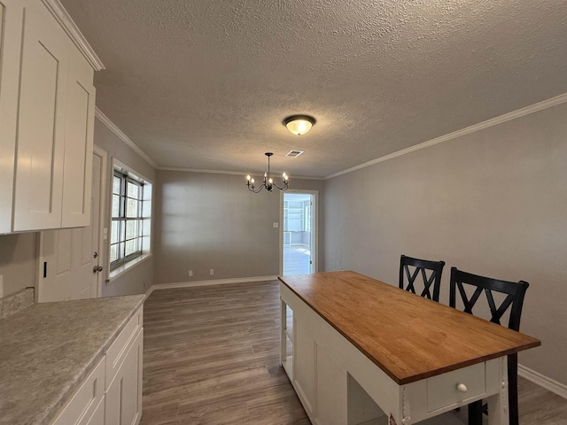 dining space featuring baseboards, visible vents, dark wood finished floors, crown molding, and a chandelier