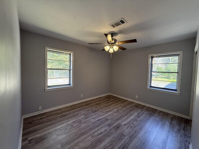 unfurnished room with ceiling fan, dark wood finished floors, visible vents, and baseboards