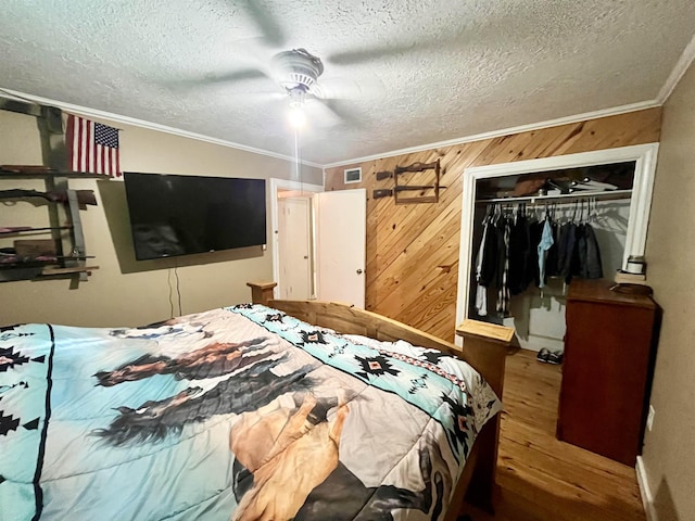 7521 Puntes Ln, Silsbee, TX 77659 - bedroom with a closet, visible vents, wooden walls, crown molding, and wood finished floors
