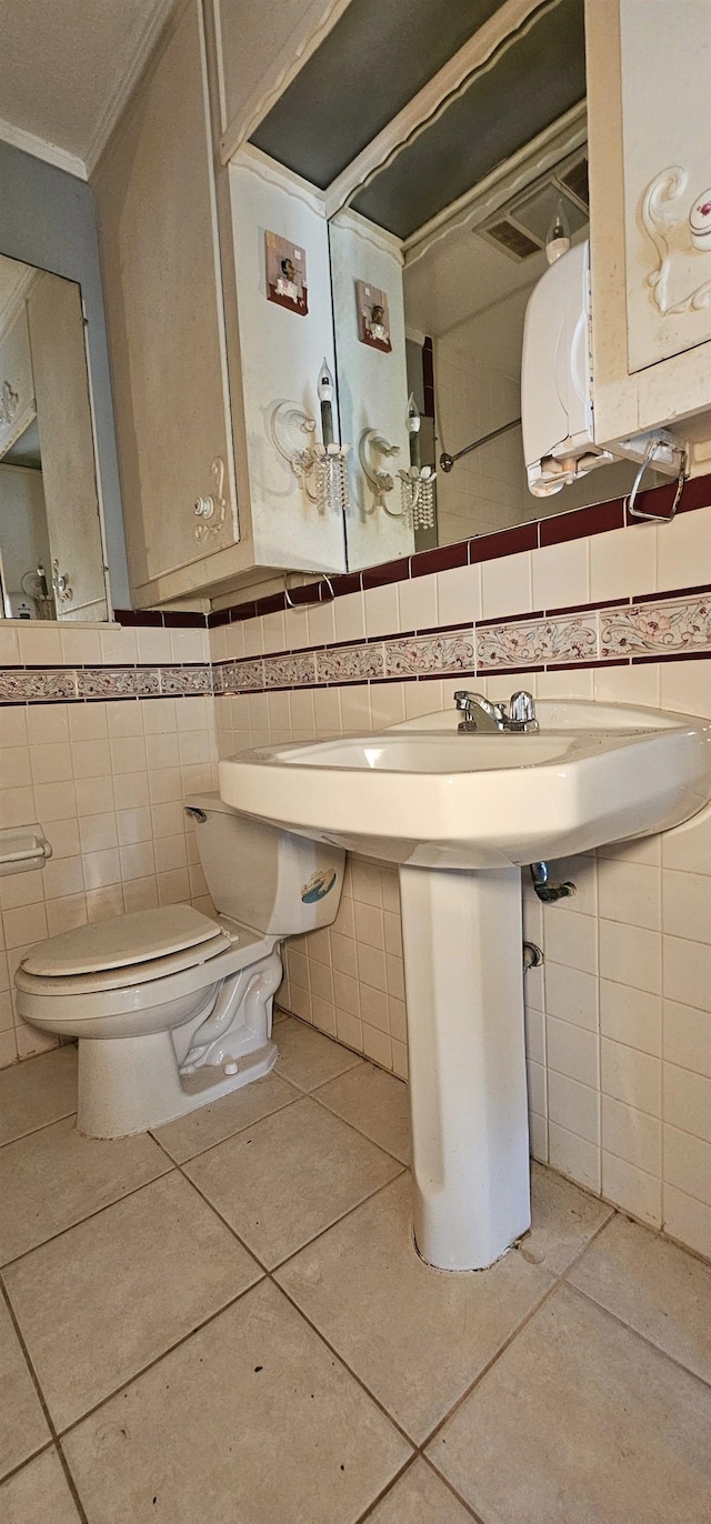 bathroom featuring ornamental molding, tile patterned floors, toilet, and tile walls