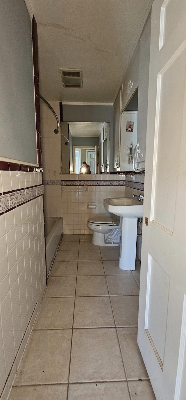 bathroom featuring tile walls, tile patterned floors, and toilet