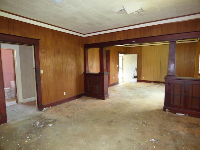 unfurnished room with crown molding and wood walls