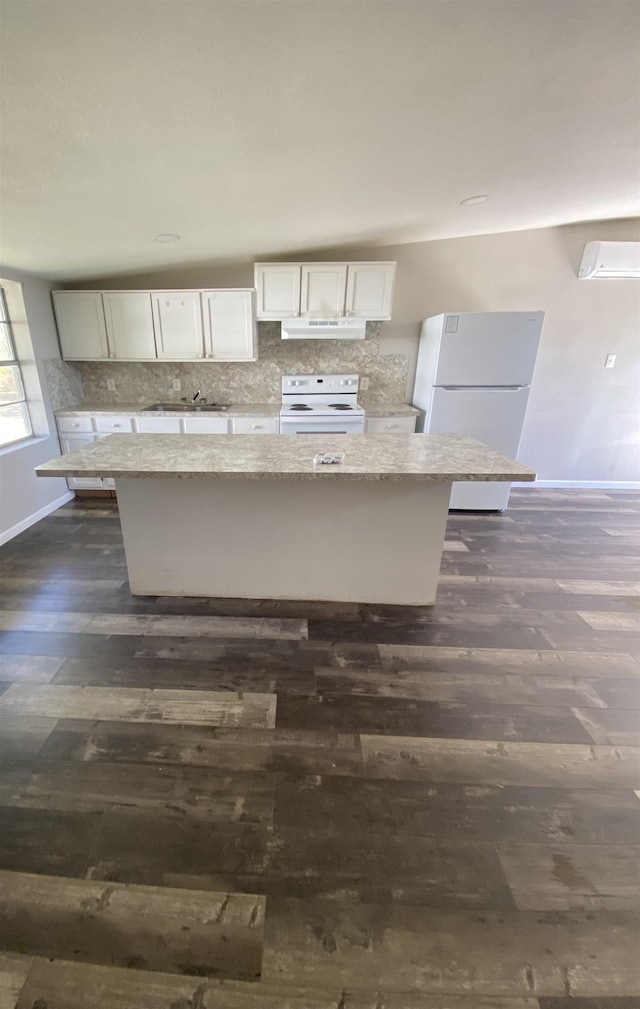 kitchen featuring light stone countertops, dark wood-type flooring, a kitchen island, white appliances, and white cabinets