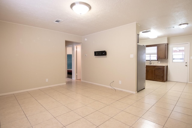 unfurnished room featuring light tile patterned floors, visible vents, and a textured ceiling