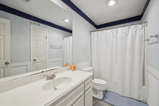 bathroom featuring toilet, vanity, a wainscoted wall, and shower / bath combo with shower curtain