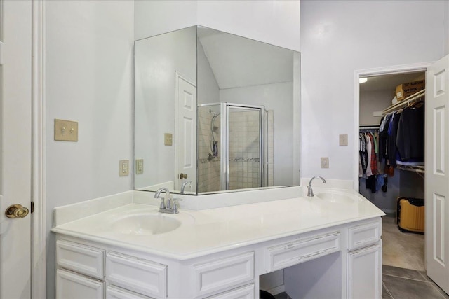 full bath featuring a stall shower, a spacious closet, double vanity, and tile patterned flooring