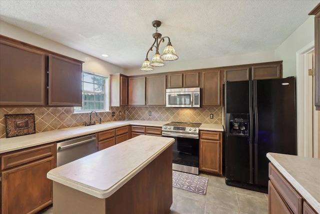 kitchen featuring stainless steel appliances, light countertops, pendant lighting, backsplash, and a textured ceiling