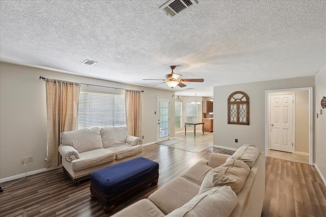 living area with a ceiling fan, baseboards, wood finished floors, and a textured ceiling
