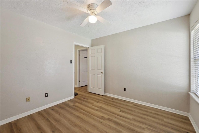 unfurnished room featuring light wood finished floors, baseboards, ceiling fan, and a textured ceiling