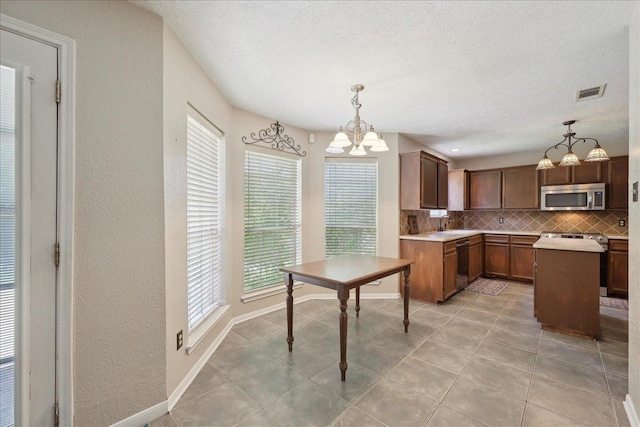kitchen with stainless steel microwave, dishwasher, backsplash, a chandelier, and healthy amount of natural light