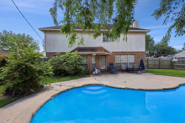 back of house with brick siding, a patio, a chimney, and fence
