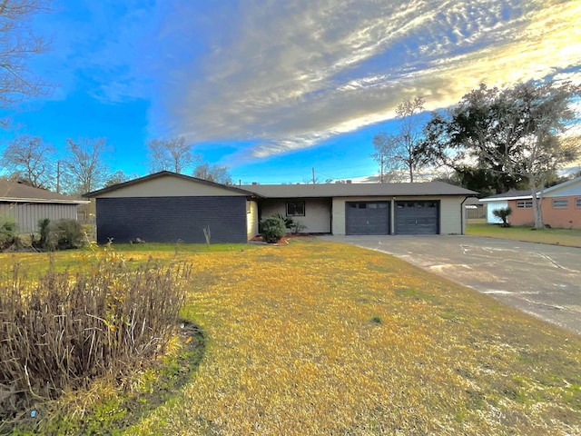 ranch-style house featuring a garage and a front lawn