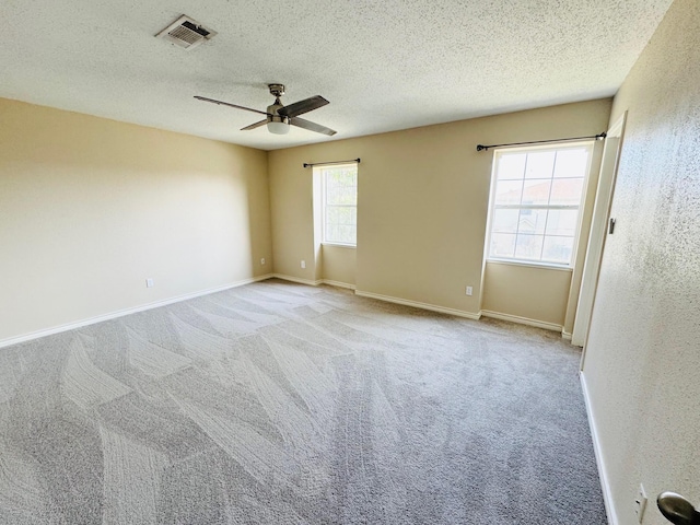 carpeted spare room featuring ceiling fan, plenty of natural light, and a textured ceiling