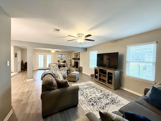 living room with ceiling fan, wood-type flooring, and a textured ceiling