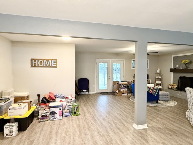 recreation room with hardwood / wood-style flooring, a brick fireplace, and french doors