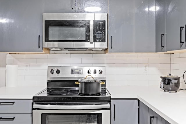 kitchen with gray cabinets, appliances with stainless steel finishes, and tasteful backsplash