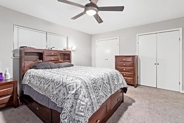 carpeted bedroom featuring ceiling fan and two closets