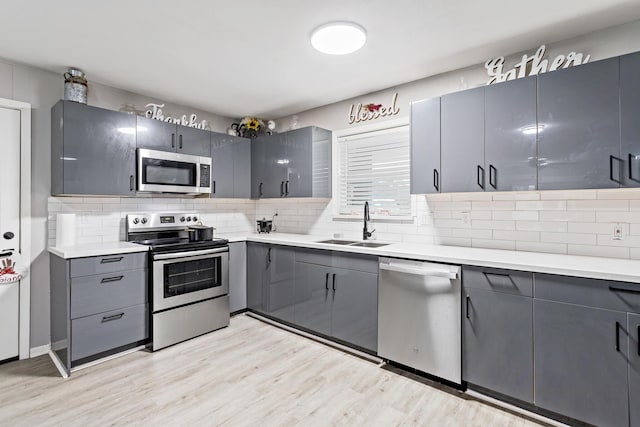 kitchen with stainless steel appliances, gray cabinets, and sink