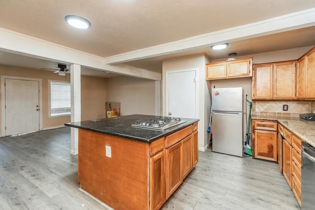 kitchen featuring appliances with stainless steel finishes, a center island, tasteful backsplash, and dark stone counters