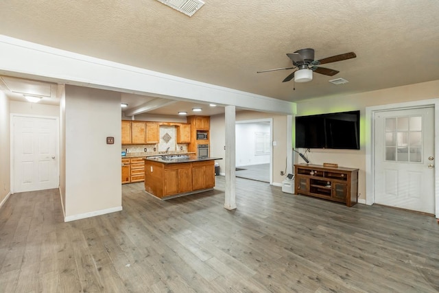 kitchen with a center island, dark wood-type flooring, ceiling fan, a textured ceiling, and appliances with stainless steel finishes