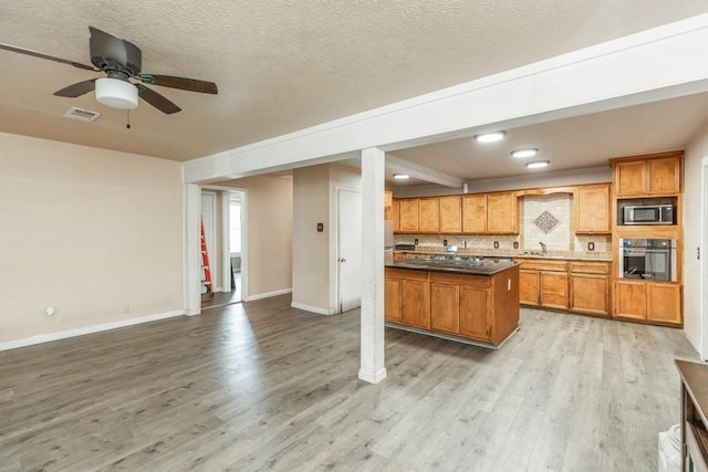 kitchen with ceiling fan, stainless steel appliances, beamed ceiling, backsplash, and light wood-type flooring