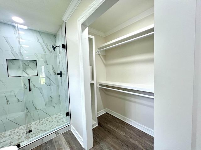 bathroom featuring hardwood / wood-style flooring, ornamental molding, and a shower with door