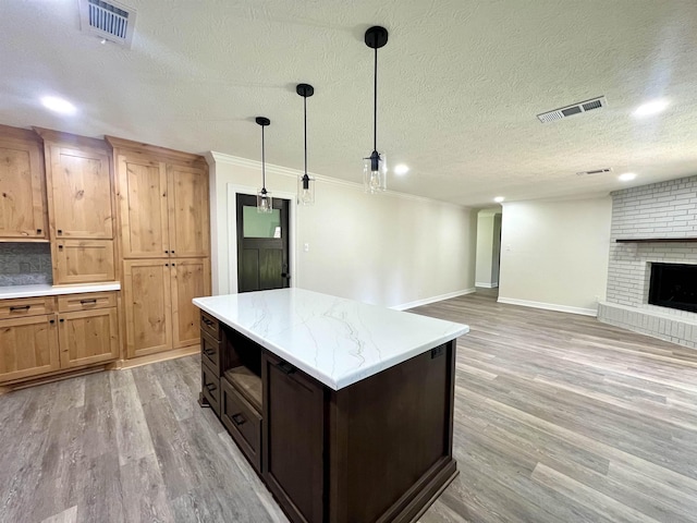 kitchen featuring a fireplace, a textured ceiling, tasteful backsplash, decorative light fixtures, and a kitchen island