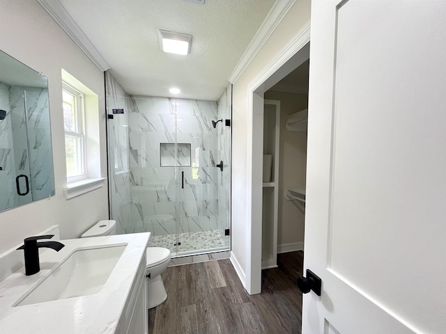 bathroom with a shower with door, crown molding, hardwood / wood-style flooring, toilet, and a textured ceiling